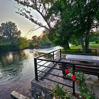 a bench sitting next to a river with flowers at Vikendica na Sani Datea in Sanski most