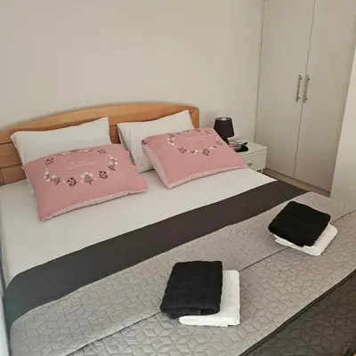 a bedroom with a bed with pink and black pillows at Vikendica na Sani Datea in Sanski most