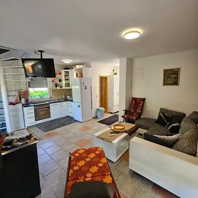 a living room with a couch and a kitchen at Vikendica na Sani Datea in Sanski most