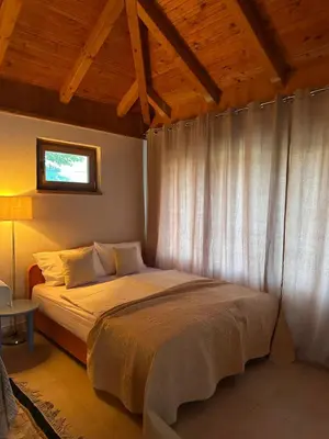 a bedroom with a large bed with a window at Oaza Vrbas - Riverside Bungalow near Jajce in Vinac