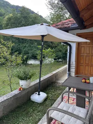 a white umbrella on a porch with a table and chairs at Oaza Vrbas - Riverside Bungalow near Jajce in Vinac