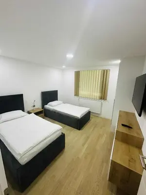 a room with two beds and a table and a television at SWISS Apartment in Pokoj