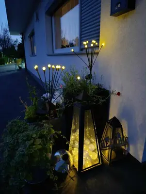 a lit up garden with a lantern and lights at SWISS Apartment in Pokoj