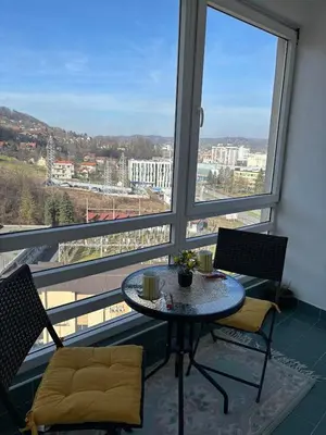 a table and chairs in a room with a large window at Apartment Meskovic in Tuzla