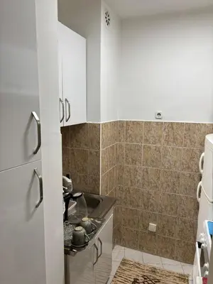 a kitchen with a sink and a tiled wall at Apartment Meskovic in Tuzla