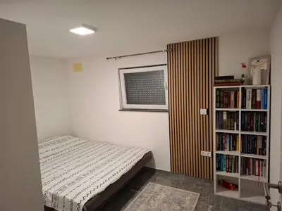 a bedroom with a bed and a book shelf with books at Apartman Ventus in Bihać