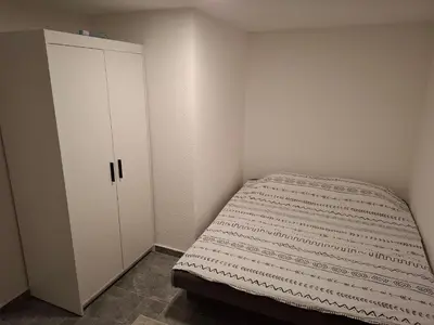 a small bedroom with a bed and a cabinet at Apartman Ventus in Bihać