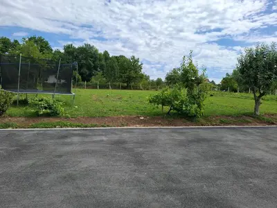 an empty parking lot with trees in a field at Apartman Ventus in Bihać