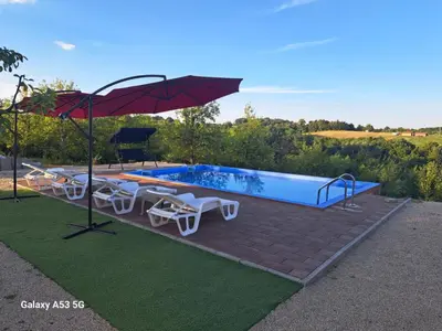 a swimming pool with an umbrella and chairs and a table at Vikendica Hangover in Gradačac
