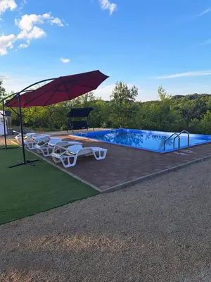 a pool with an umbrella and chairs and a table at Vikendica Hangover in Gradačac
