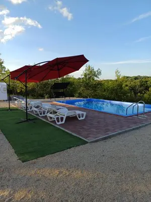 a pool with a red umbrella and chairs and a table at Vikendica Hangover in Gradačac