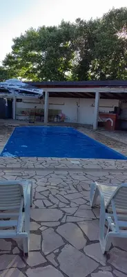 a blue swimming pool with two chairs and a building at Villa S&M in Ivišovo Greblje