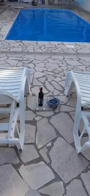 two white benches and a bottle of wine on a stone patio at Villa S&M in Ivišovo Greblje