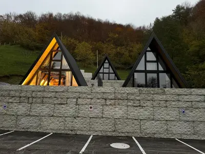 a building with a stone wall in a parking lot at Wooden Houses D&D in Jajce
