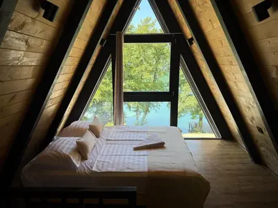 a bed in a room with a large window at Wooden Houses D&D in Jajce