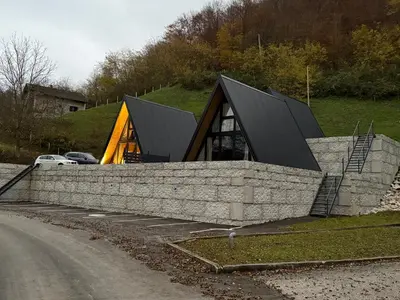 a house with a black roof and a stone wall at Wooden Houses D&D in Jajce