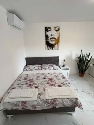 a white bedroom with a bed with a flower bedspread at Stan na dan - zvijezda Danica Kozarska Dubica in Bosanska Dubica