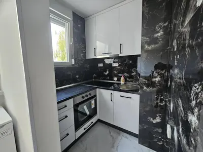 a black and white kitchen with white cabinets and a window at Stan na dan - zvijezda Danica Kozarska Dubica in Bosanska Dubica