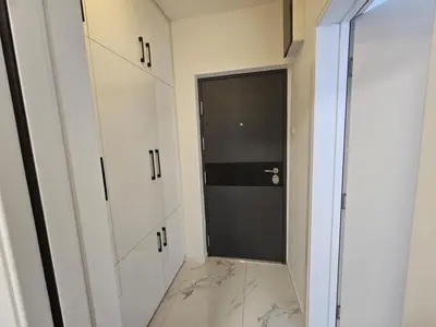 a hallway with white cabinets and a black door at Stan na dan - zvijezda Danica Kozarska Dubica in Bosanska Dubica