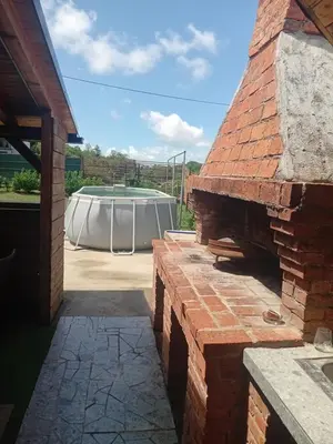 an outdoor brick oven with a table in the background at Vikendica Lazar in Banja Luka