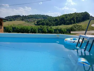 a blue swimming pool with a chair and a table at Vikendica Lazar in Banja Luka