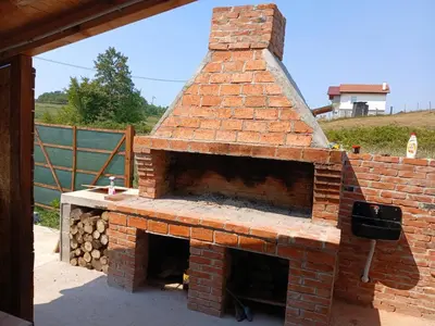 an outdoor brick oven with a pile of logs at Vikendica Lazar in Banja Luka