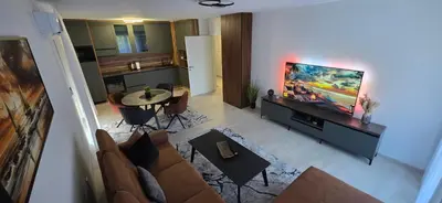 a living room with a couch and a tv and a table at SkyDeck8 in Cazin