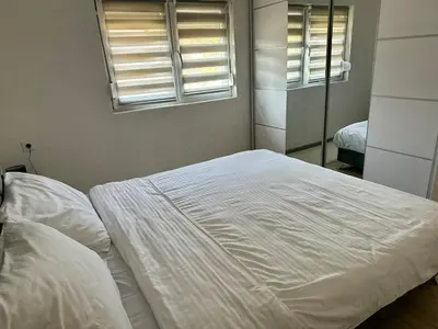 a white bed in a bedroom with two windows at Hilltop Family House Panoramic Views in Dobrnja