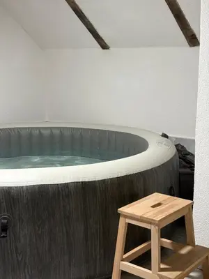 a hot tub in a room with a wooden stool at Lux Escape Pridolci in Kozica