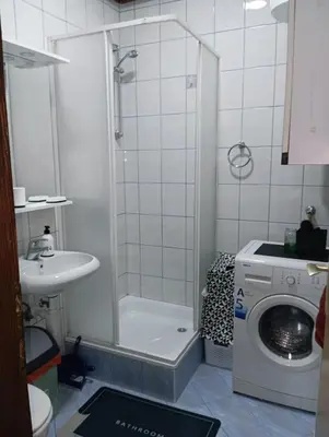 a bathroom with a shower and a washing machine at Tuzla Stay Apartment in Tuzla
