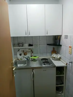 a kitchen with a sink and a stove and white cabinets at Tuzla Stay Apartment in Tuzla