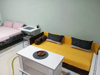 a living room with a yellow couch and a table at Tuzla Stay Apartment in Tuzla