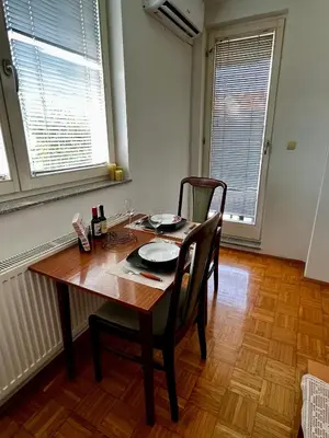 a dining room with a table and chairs and two windows at Nataša in Doboj