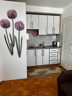 a kitchen with white cabinets and purple flowers on the wall at Nataša in Doboj
