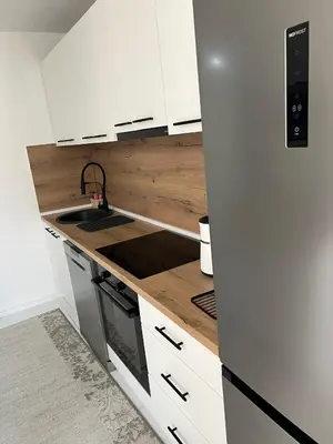 a kitchen with white cabinets and a wooden counter top at EMMA apartman in Travnik