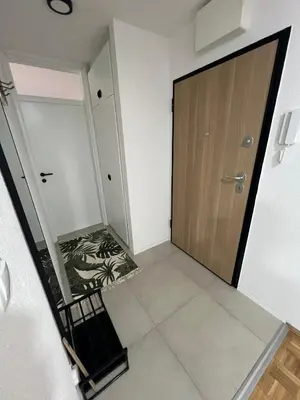 an empty hallway with a wooden door and a staircase at EMMA apartman in Travnik