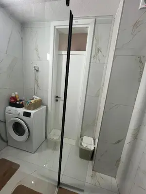 a bathroom with a washing machine and a shower at EMMA apartman in Travnik