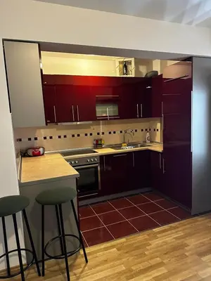 a kitchen with red cabinets and a counter and bar stools at Beauty Room Apartman in Prnjavor
