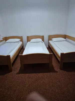 three twin beds in a room with a wall at Sobe Kovacevic