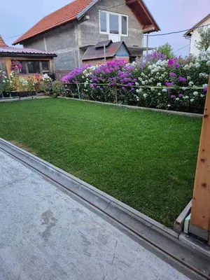 a yard with grass and flowers in front of a house at Sobe Kovacevic
