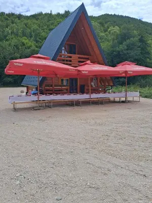 a log cabin with red umbrellas in front of it at Whisper of the Pliva in Šipovo