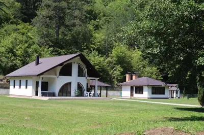 a white house with a black roof in a field at Villa Duboka Bugojno in Bugojno