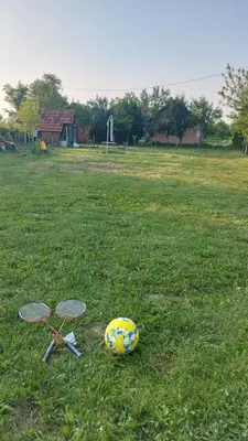 two tennis rackets and a ball on the grass at MALA KOLA - Weekend House in Banja Luka