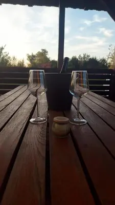 two wine glasses sitting on top of a wooden table at MALA KOLA - Weekend House in Banja Luka
