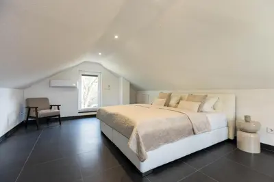 a white bedroom with a bed and a chair at NADA Home in Čelebić