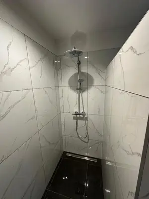 a bathroom with a shower with white marble walls at NADA Home in Čelebić
