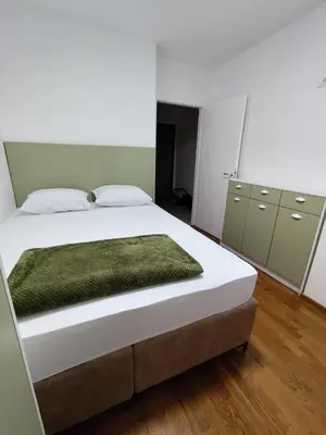 a bedroom with a large white bed and green cabinets at AnyBL03 in Železnička Stanica Incel
