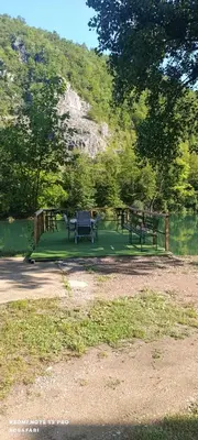 a picnic table and benches in a park next to a lake at Holiday home SaFari in Bosanska Krupa