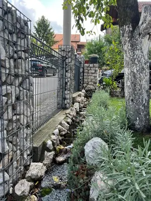 a garden with a stone fence and a tree at Apartman Omerovic - Panon Centar Tuzla in Tuzla