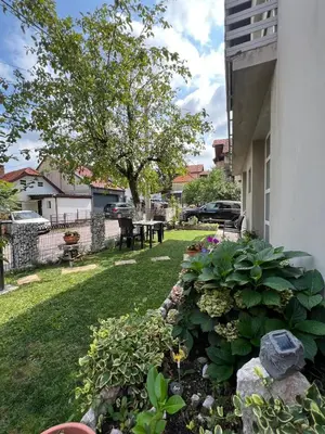 a garden with flowers and a table in a yard at Apartman Omerovic - Panon Centar Tuzla in Tuzla